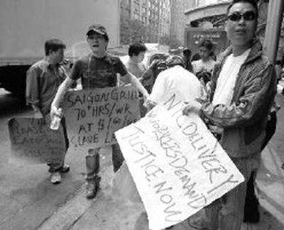 
Signs are distributed to pickets outside Saigon Grill on New York's Upper West Side before a protest in front of the restaurant on Wednesday. Workers at the Saigon Grill, a small chain of Vietnamese cafes, filed a lawsuit seeking back pay in March. 
 (Associated Press / The Spokesman-Review)
