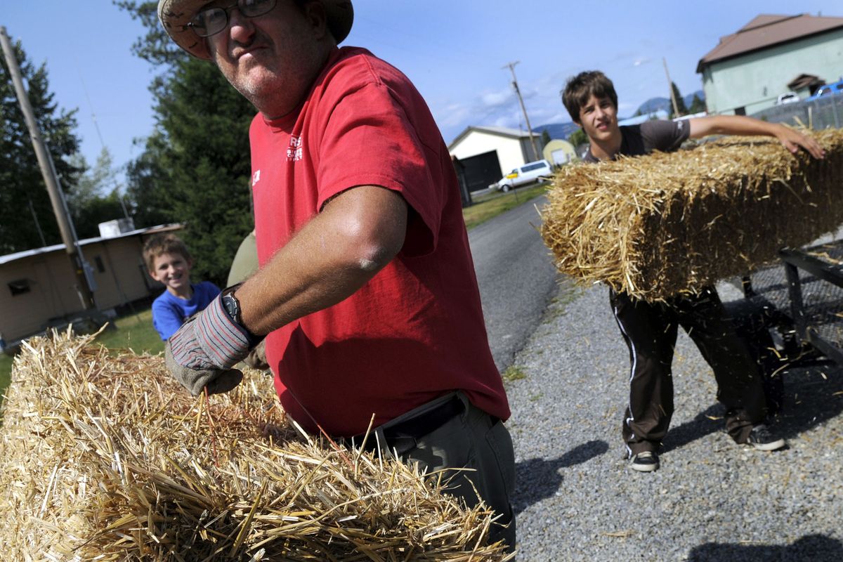 Athol resident David Harms, with Coby Shaffer, 9, left, and Spencer Hansen, 14, prepare for the money-in-the-straw game in Athol on Friday. At least $500 was hidden in bales of straw as part of Athol Daze. (Kathy Plonka / The Spokesman-Review)
