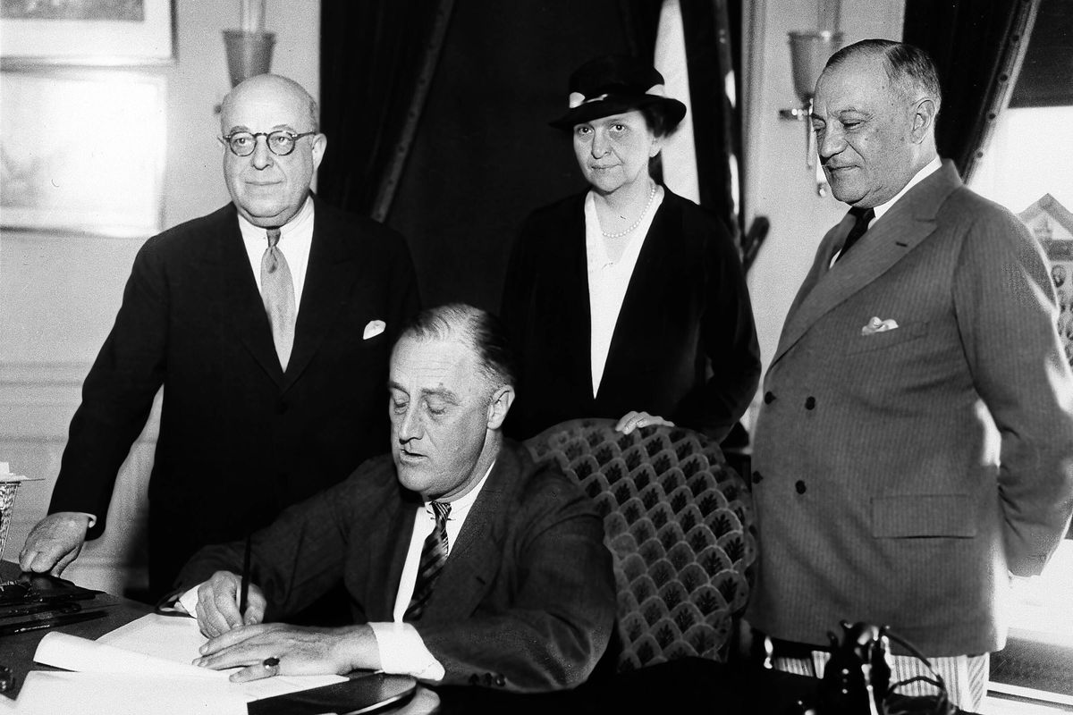In this June 6, 1933 photo, President Franklin D. Roosevelt is shown signing the Wagner Unemployment Bill at the White House in Washington. Standing, from left are: Rep. Theodore A. Peyser, D-N.Y.; Labor Secretary of Labor Frances Perkins; and Sen. Robert Wagner, D-N.Y.  (STF)