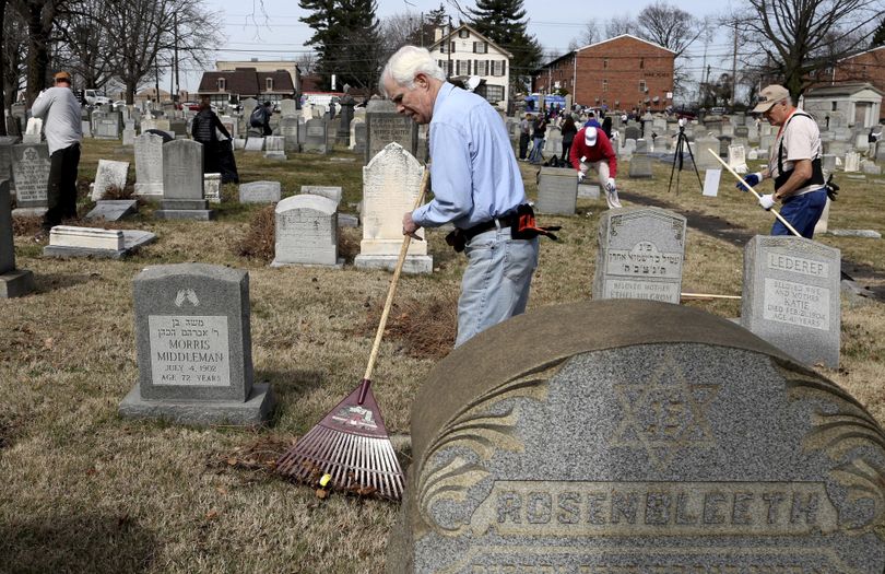 Volunteer John Walsh from northeast Philadelphia rakes debris at Mount Carmel Cemetery on Tuesday, Feb. 28, 2017, in Philadelphia. (Jacqueline Larma / Associated Press)