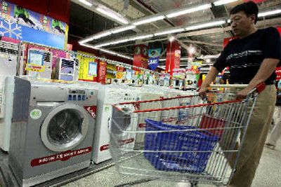 
A Chinese man pushes a shopping cart past washing machines, some manufactured by home appliances giant Haier at a shopping mall in Beijing earlier this month. China is moving into the merger and acquisitions major leagues. 
 (Associated Press / The Spokesman-Review)