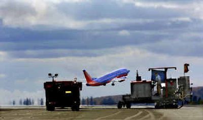 
While a machine cuts grooves in the main runway, a Southwest Airlines jet takes off from Spokane International Airport's secondary strip. 
 (Christopher Anderson/ / The Spokesman-Review)