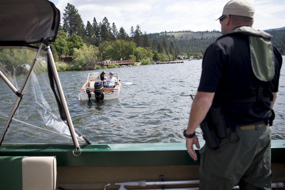 Spokane County sheriffs Deputy James Ebel offers aid to boaters suffering from a power failure after checking them for equipment violations on Thursday, May 26, 2016, at Liberty Lake, Wash. (Tyler Tjomsland / The Spokesman-Review)