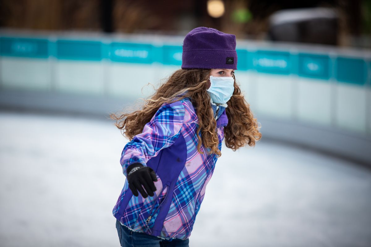 Naomi Hartman wears a mask while enjoying the Numerica Skate Ribbon at Riverfront Park in downtown Spokane on Sunday. Opening day for the ice skating season was Saturday, and amid the coronavirus pandemic, patrons are required to reserve time on the ice in advance in order to observe social distancing, as well as wear a mask and gloves while skating.  (Libby Kamrowski/ THE SPOKESMAN-REVIEW)