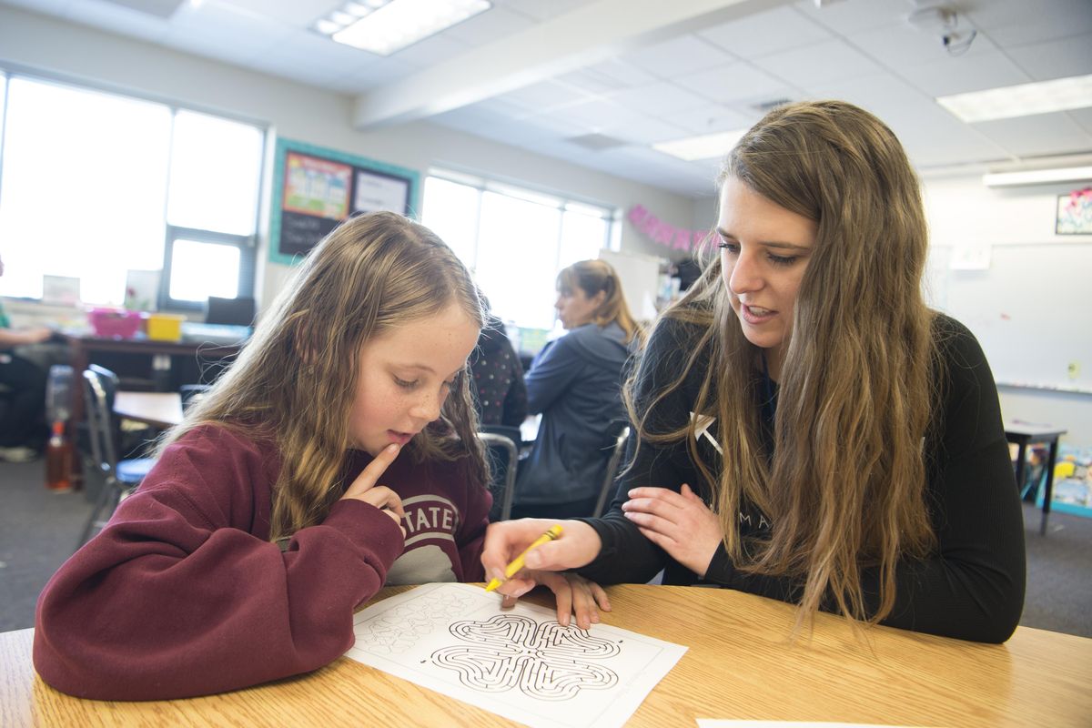 Fourth-grader Emily Westerlund, left, solves puzzles during mentor hour with mentor Mason Jaeger, an Eastern Washington University student Tuesday at Sunset Elementary, one of the schools that use volunteers to spend time with kids, help them solve problems and learn to be resilient. (Jesse Tinsley / The Spokesman-Review)