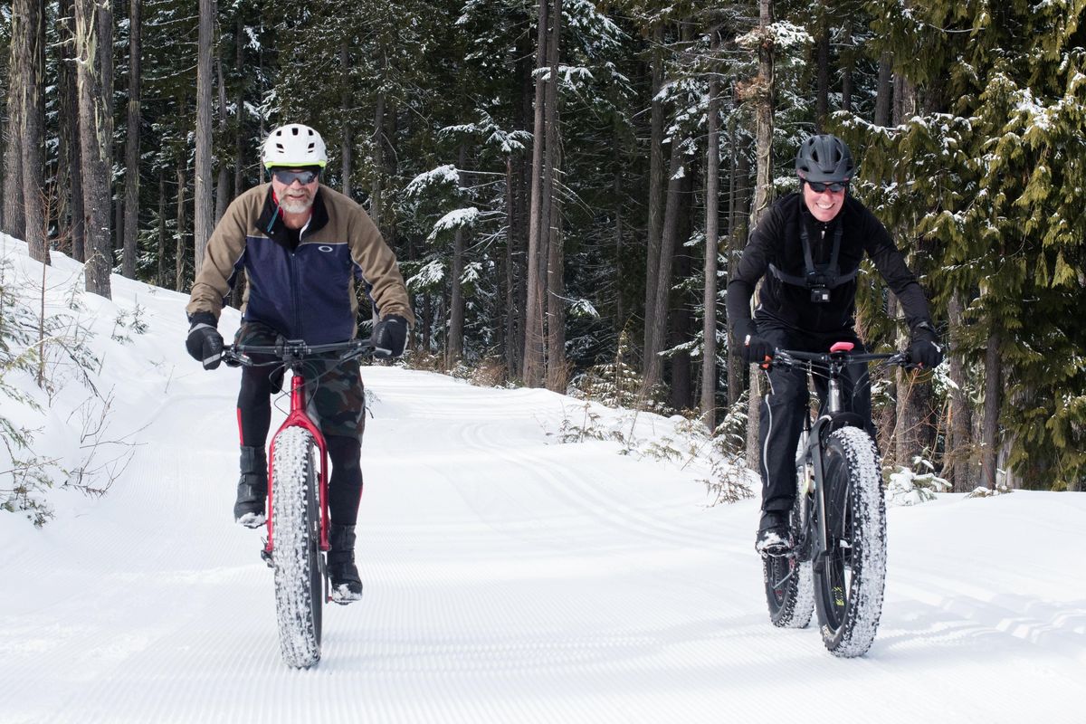 Frank Benish, left, and Brent Schlangen are all smiles while riding their fat bikes at 49 Degrees North on Monday, Feb. 24, 2020. (Eli Francovich / The Spokesman-Review)