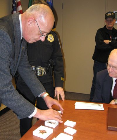 Dennis Griffiths, historian of the Oregon State Sheriff’s Association, displays the three shooting badges and the star badge originally presented to former Spokane Police Chief Joel Warren in 1887.  (Lisa Leinberger / The Spokesman-Review)