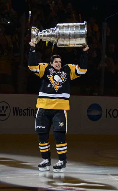 Pittsburgh center Sidney Crosby skates the Stanley Cup onto the ice before the Penguins faced the Washington Capitals. (Fred Vuich / Associated Press)