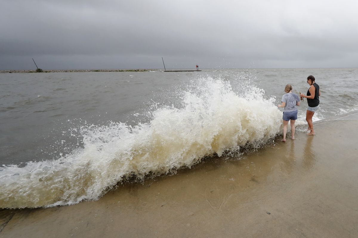 Erin Shaw, left, and Brittany Schanzbach stand near crashing waves near the seawall of Lake Pontchartrain from a storm surge in New Orleans, Sunday, June 7, 2020, as Tropical Storm Cristobal approaches the Louisiana Coast.  (Gerald Herbert)