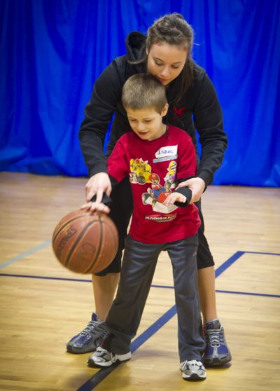 Volunteer Jamie Palmer helps Isaac Mitchell, 5, with his dribbling skills at the Warehouse in Spokane on Feb. 12. (Colin Mulvany)