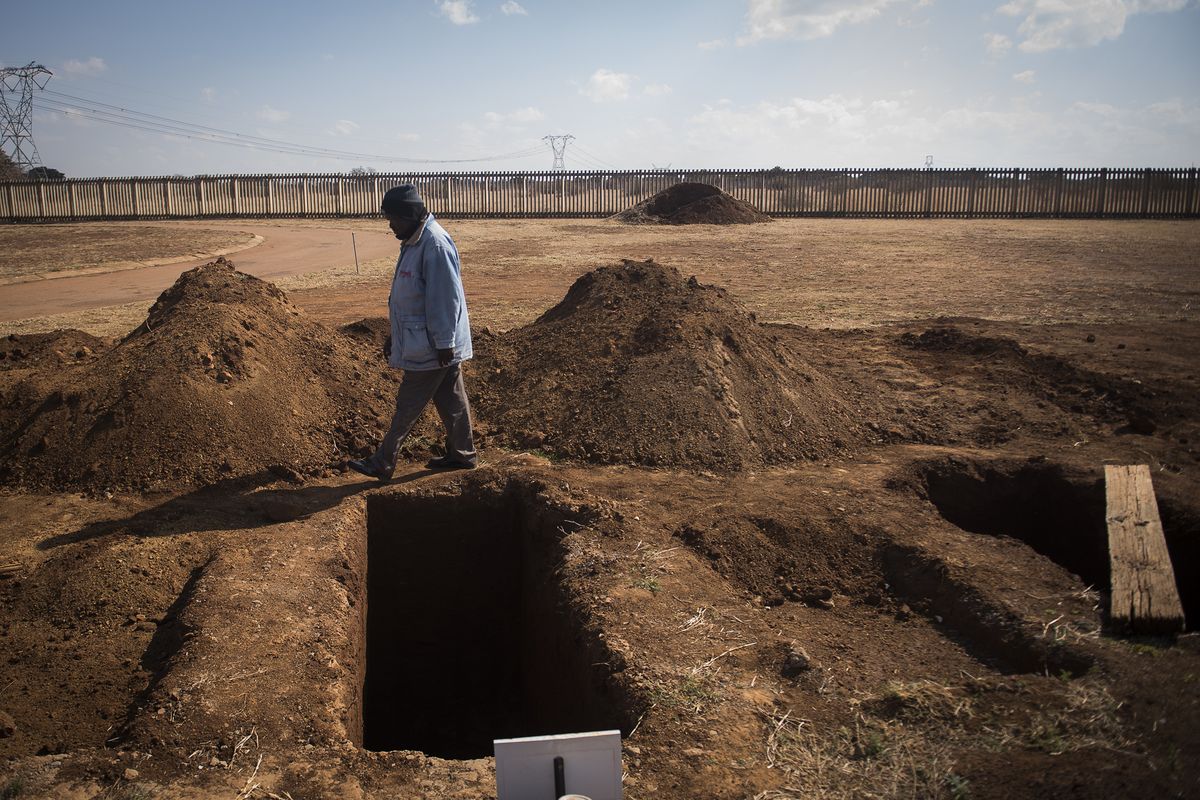 A worker walks past a freshly-dug graves at the Honingnestkrans Cemetery, North of Pretoria, South Africa, Thursday, July 9, 2020. The Africa Centers for Disease Control and Prevention says the coronavirus pandemic on the continent is reaching "full speed" after cases surpassed a half-million and a South African official said a single province is preparing 1.5 million grave.  (Shiraaz Mohamed)