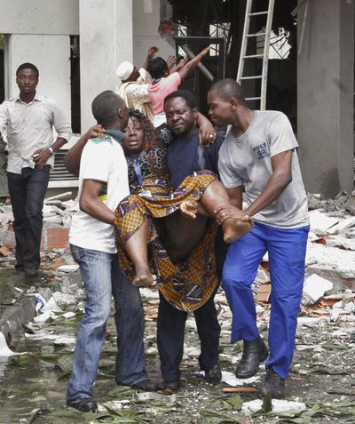 An injured woman is carried from a United Nations office in Abuja, Nigeria, on Friday after a car laden with explosives rammed through two gates and blew up. (Associated Press)