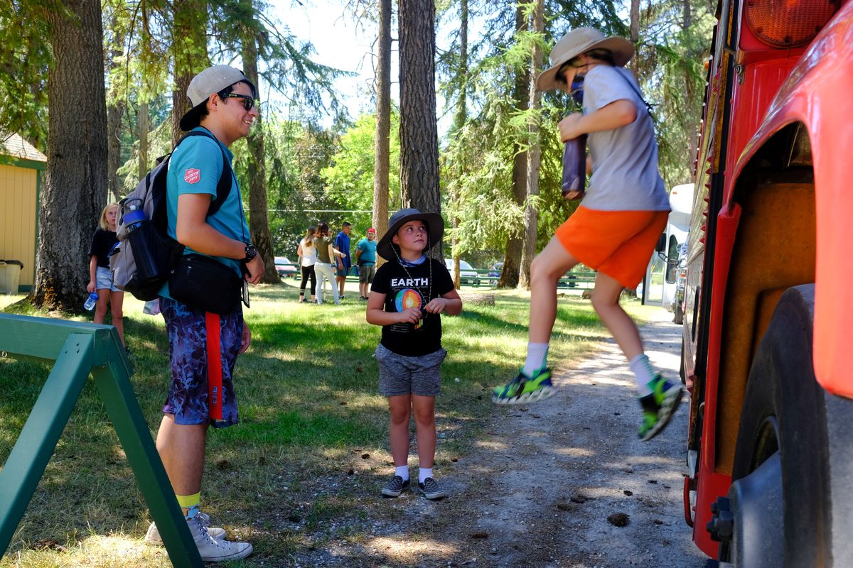 Eager camper Dawson Lester, 10, right, leaps from a bus as he arrives at Camp Gifford as his counselor Tony Worthen, left, and fellow camper Ethan Stevens, 10, center, react on June 28 at Camp Gifford, the Salvation Army’s 100-year-old camp near Deer Lake.  (Tyler Tjomsland/The Spokesman-Review)