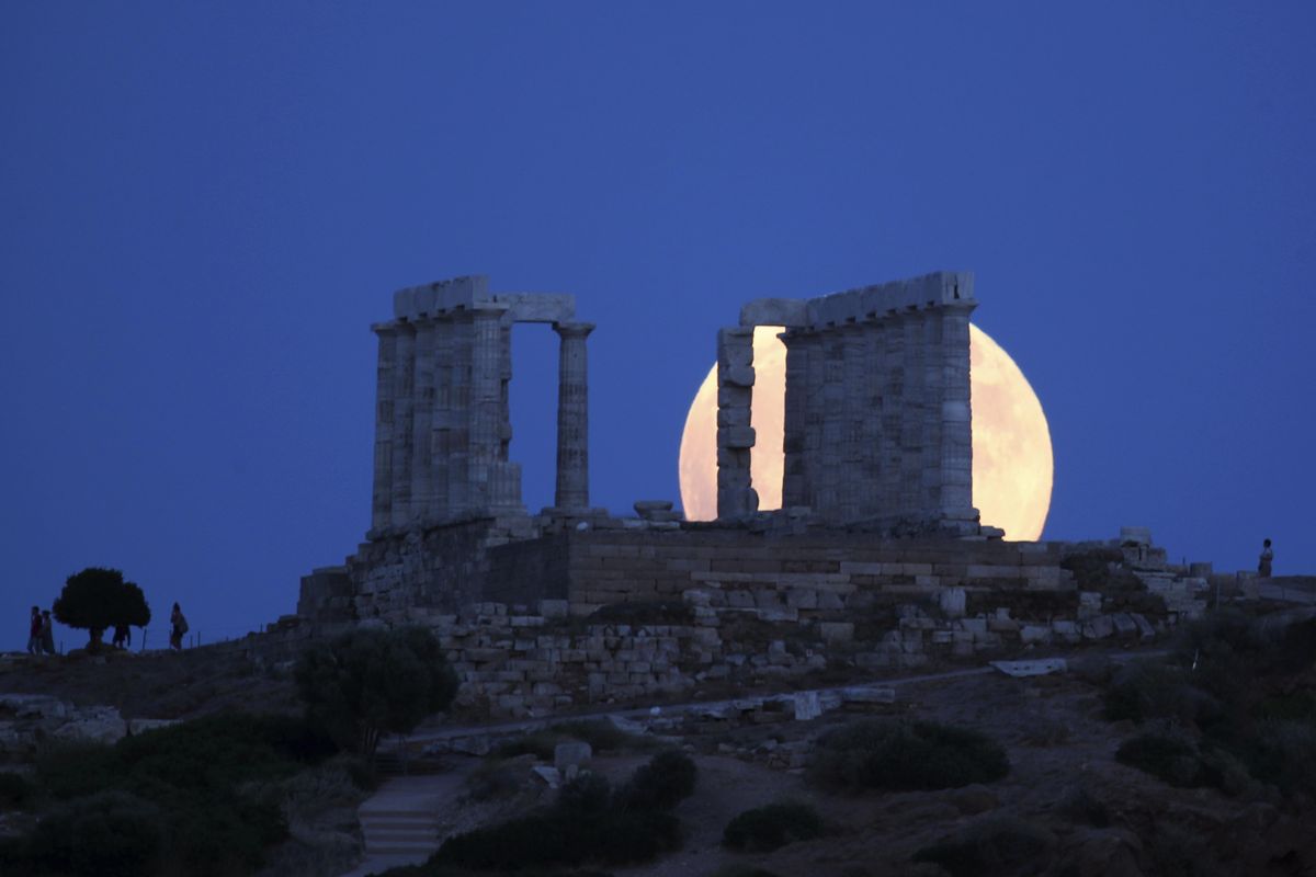 A full moon rises behind the ancient temple of Poseidon in cape Sounio, about40 miles south of Athens, Friday, July 27, 2018. The complete lunar eclipse Friday when the sun, Earth and moon line up perfectly to cast Earth’s shadow on the moon, will be the longest this century. It’s called a “blood moon” because it turns a deep red and will be visible at different times around the world. Additionally, Mars and the sun will be on exact opposite sides of the Earth and will shine its best. (Thanassis Stavrakis / Associated Press)