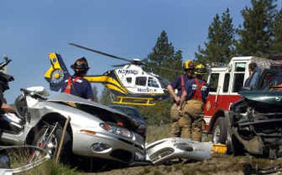 
Firefighters clean up after a crash Monday on Wandermere Road as a helicopter leaves the scene with a woman injured in the accident.
 (Jed Conklin / The Spokesman-Review)