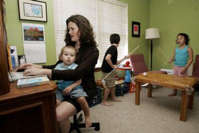 
Malena Lott uses the computer at her desk as her 16-month-old son, Owen, sits on her lap, and her daughter Audrey, 6, right, and son Harrison, 8, play at a homemade pool table in her home office in Edmond, Okla. She credits her coach with helping her bring peace to her busy life.
 (Associated Press / The Spokesman-Review)