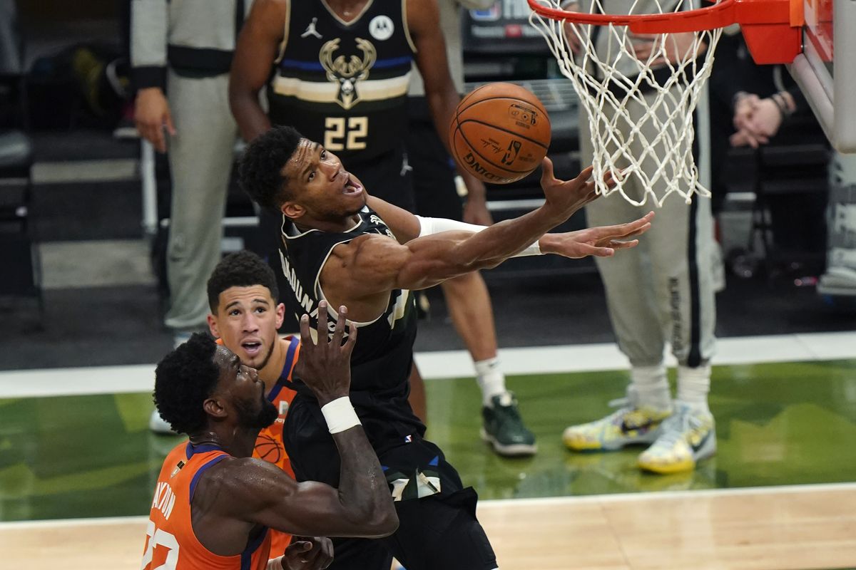 Milwaukee Bucks forward Giannis Antetokounmpo (34) goes to the basket over Phoenix Suns center Deandre Ayton (22) and guard Devin Booker during the second half of Game 6 of basketball's NBA Finals in Milwaukee, Tuesday, July 20, 2021.  (Associated Press)