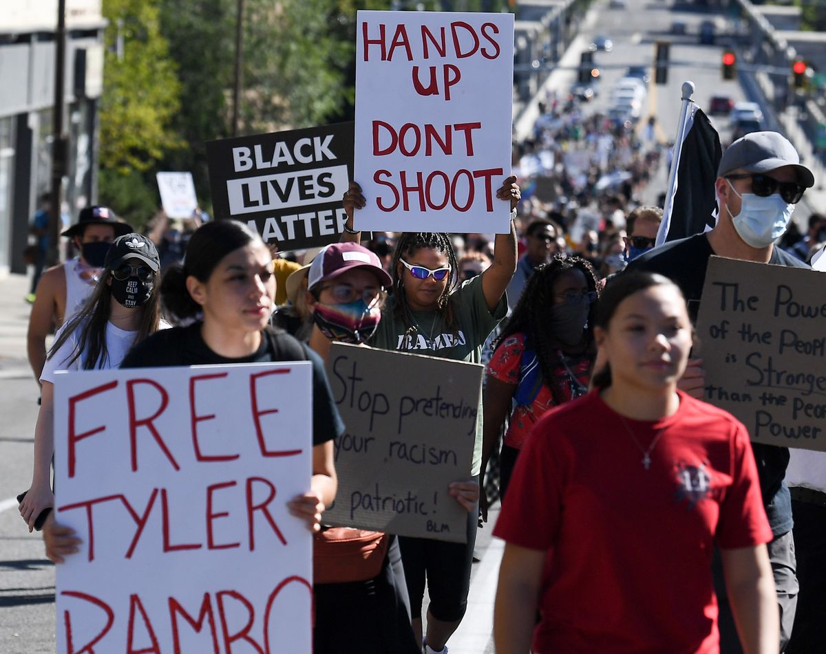 Nicole Ellis, center, mother of Tyler Rambo who was shot by police 14 times in 2019 holds a "hands up dont shoot sign" as she marches during a Black Lives Matter protest and march on Sunday, Aug. 30, 2020, in Spokane, Wash.  (Tyler Tjomsland/THE SPOKESMAN-REVIEW)