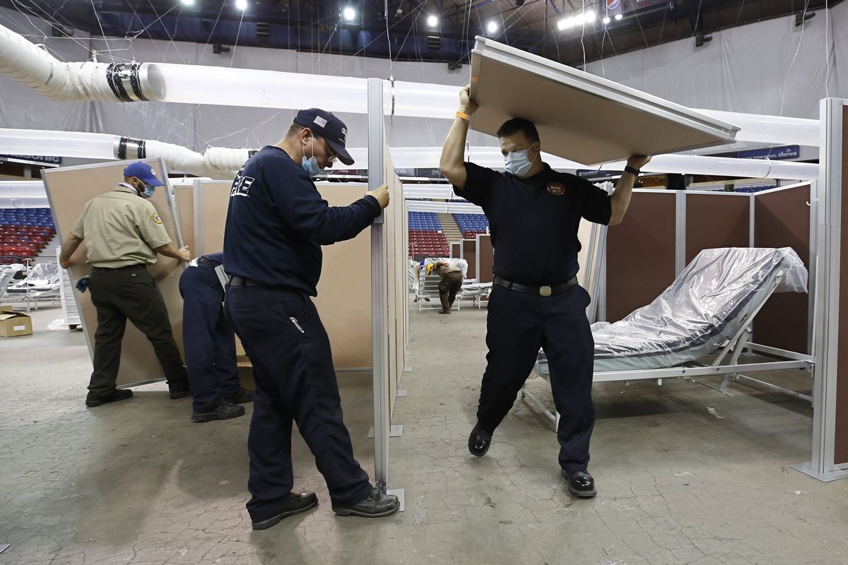 FILE — In this April 18, 2020 file photo partitions are installed between beds as work is performed to turn Sleep Train Arena into a 400-bed emergency field hospital to help deal with the coronavirus, in Sacramento, Calif. The state has reopened the arena and other facilities to help handle a new surge of coronavirus patients, but is using little more than a handful of volunteers from Gov. Gavin Newsom