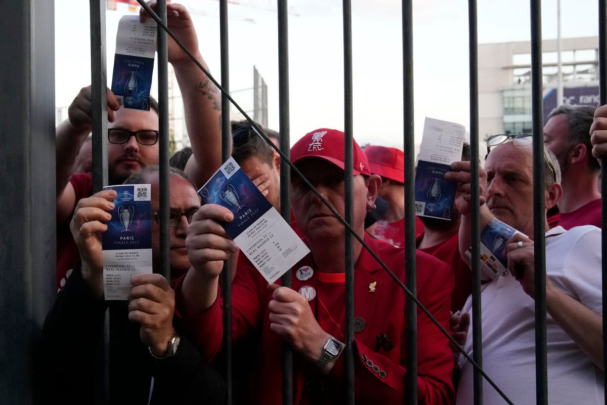 Liverpool fans show tickets and wait in front of the Stade de France prior the Champions League final soccer match between Liverpool and Real Madrid, in Saint Denis near Paris, Saturday, May 28, 2022. Police have deployed tear gas on supporters waiting in long lines to get into the Stade de France for the Champions League final between Liverpool and Real Madrid that was delayed by 37 minutes while security struggled to cope with the vast crowd and fans climbing over fences.  (Christophe Ena)
