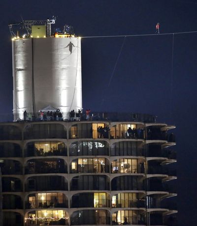 The shadow of daredevil Nik Wallenda is cast against the Marina City west tower as he begins his tightrope walk. (Associated Press)