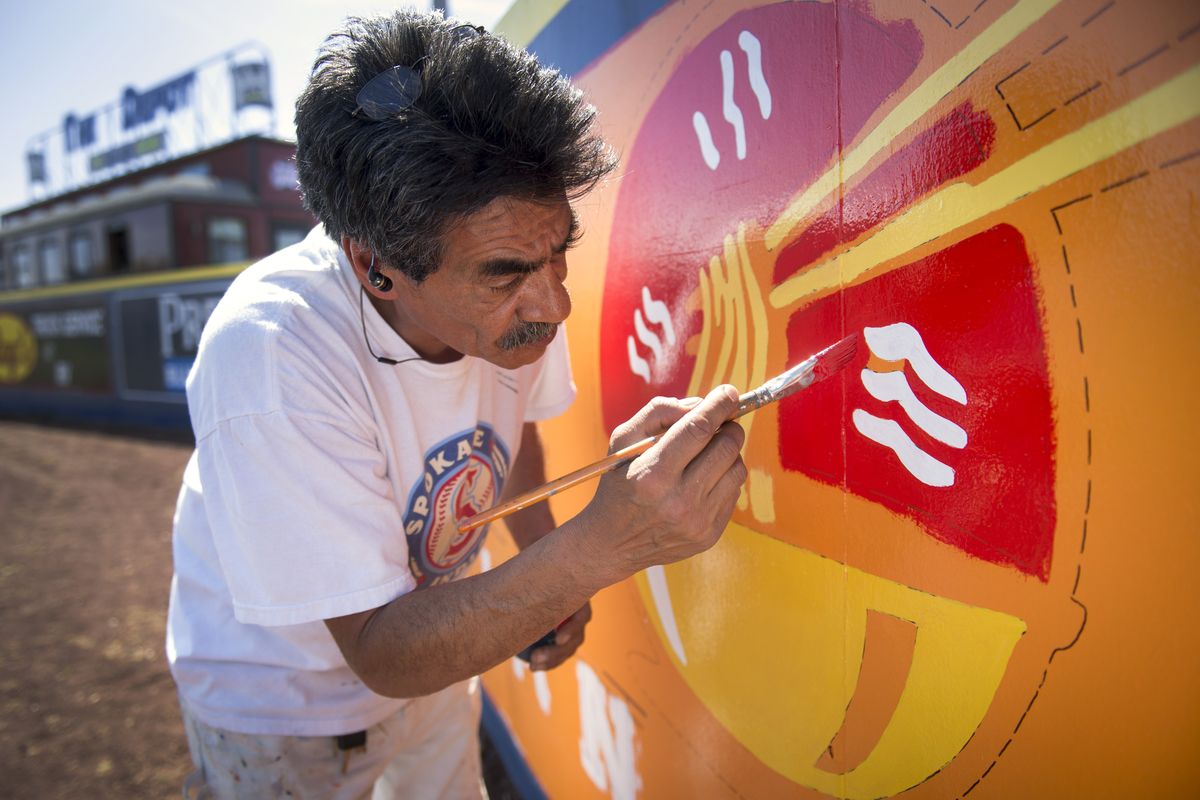 “I’m an analog man in a digital world,” said Ruben Marcilla, in his 25th season as a painter who creates the outfield signs at Avista Stadium. From the back of his beat-up Subaru wagon (pictured below), he prepares to paint an ad in right field. (Colin Mulvany)