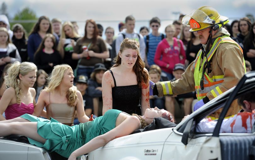 East Valley High School student Sierra Nalder, in black, acts the part of drunken driver while she looks at a bloody mock crash on Thursday on the road outside the school. The mock crash, staged in front of the student body with firefighters, law enforcement and even funeral home personnel, illustrated the consequences of drinking and driving. (Jesse Tinsley)