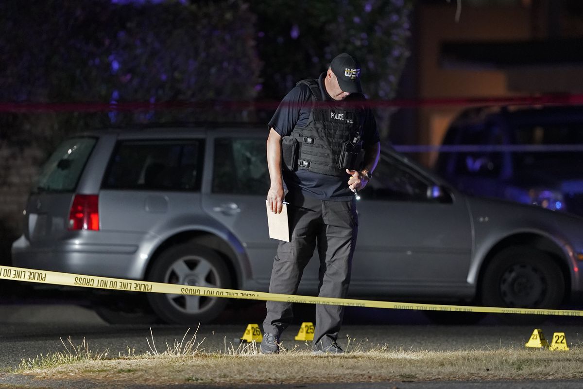 A Washington State Patrol official walks near evidence markers and a car with broken windows, Thursday, Sept. 3, 2020, in Lacey, Wash. at the scene where Michael Reinoehl was killed Thursday night as investigators moved in to arrest him. Reinoehl had been suspected of fatally shooting a supporter of a right-wing group in Portland, Oregon, last week after a caravan of Donald Trump backers rode through downtown Portland.  (Ted S. Warren)