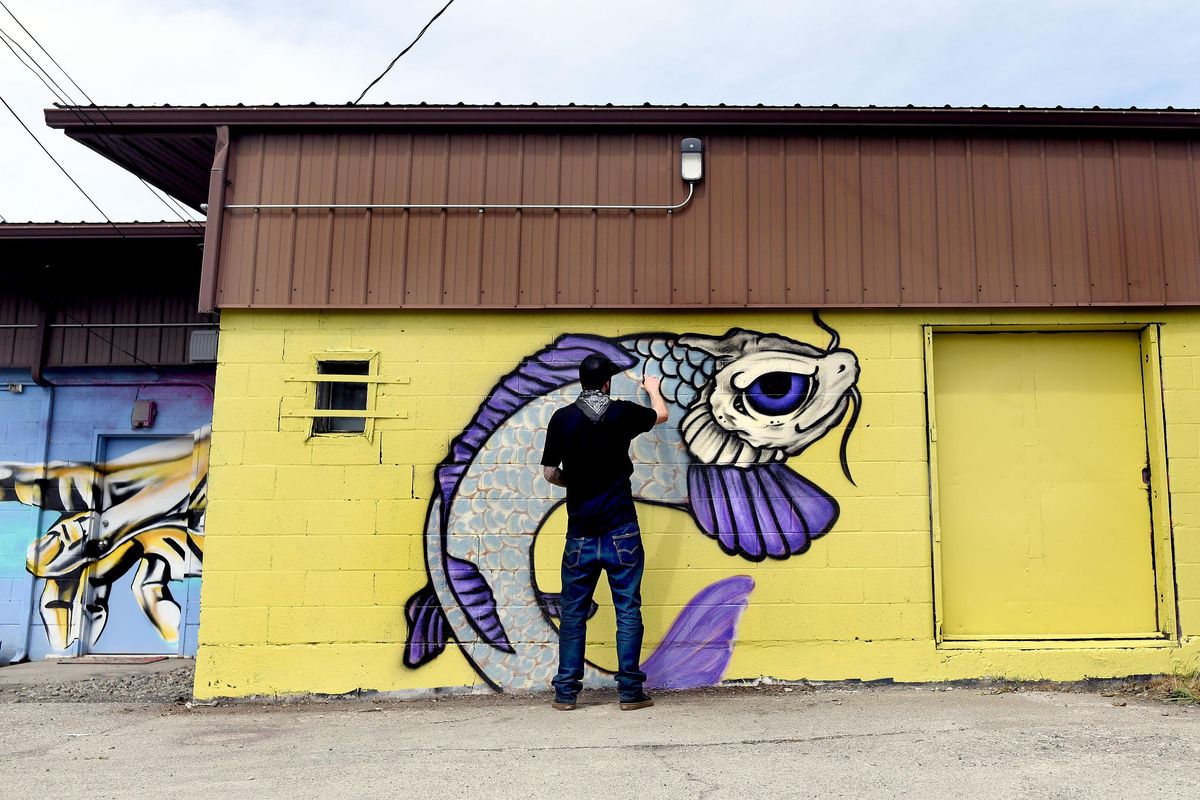 Artist Tyler Cinstar spray paints a mural in the Garland District during Art on the Go, a citywide drive-up art show in Spokane on Saturday, May 2, 2020. (Kathy Plonka / The Spokesman-Review)