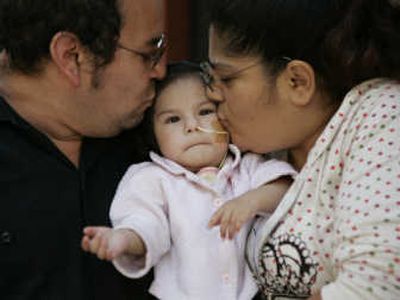 
Victor and Maria Roa kiss their daughter, Hazelle, on Monday. Hazelle has a disorder that is likely to require specialized care in the U.S., but her parents have been ordered out of the country. Associated Press
 (Associated Press / The Spokesman-Review)