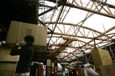 
Workers haul boxes of furniture from a Walker's Furniture storage building in East Wenatchee  on Monday, after the building's roof was blown off in Sunday's windstorm. 
 (Associated Press / The Spokesman-Review)