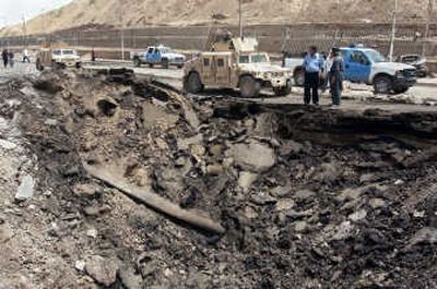 
U.S. soldiers and Iraqi police vehicles stand near the crater left behind when a suicide bomber detonated a truck wired with explosives  Monday in Kirkuk. Associated Press
 (Associated Press / The Spokesman-Review)