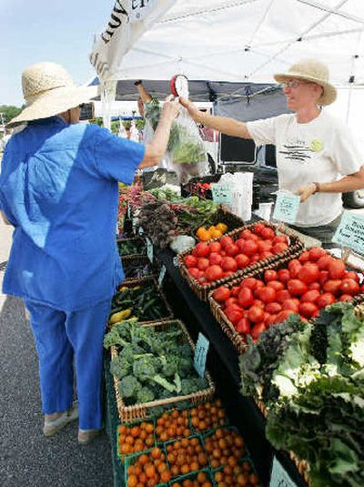 
Claire Strader, right, of Troy Community Farm helps a customer with fresh produce at the North Side Farmers' Market last month in Madison, Wis. 
 (Associated Press / The Spokesman-Review)