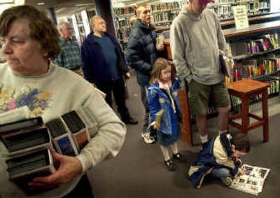 
Casey Fitzpatrick, 6, gets a head start on reading while waiting in the checkout line Tuesday at the Spokane Public Library's Shadle branch.  
 (Brian Plonka / The Spokesman-Review)
