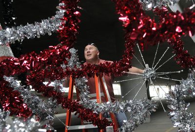 Jac Cates works to set up the Wenatchee Apple Blossom Festival float  under an overpass Friday in Spokane. Cates will drive the float in tonight’s Lilac Parade.  Forecasters expect a low of 48 degrees, dropping from a sunny high near 74 in Spokane.  (Dan Pelle / The Spokesman-Review)
