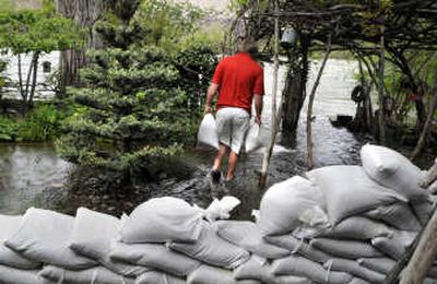 
Mark Reilly, director of the Peaceful Valley Community Center, piles sandbags against the rising water of the Spokane River. 
 (Dan Pelle / The Spokesman-Review)
