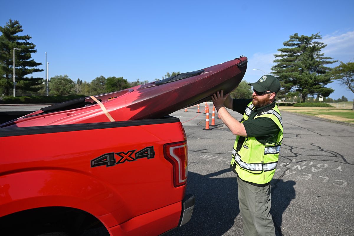 Watercraft Inspector Derek de Haas walks around a kayak whose owner was headed to the Spokane River on Tuesday at the inspection station at the Idaho state line near the westbound lanes of Interstate 90.  (Jesse Tinsley/The Spokesman-Review)