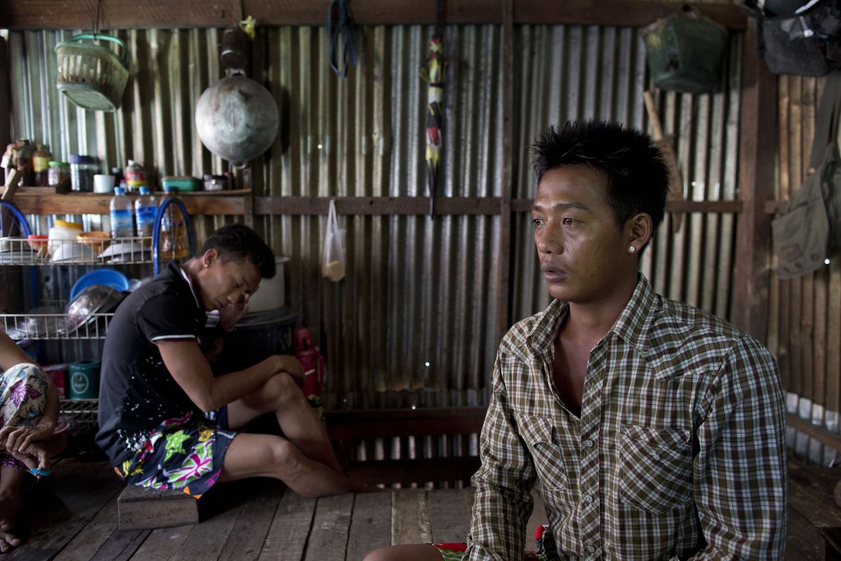 Burmese former slave fisherman Lin Lin, right, talks about friends missing at sea as Kaung Htet Wai smokes a cigarette in a shack near Yangon, Myanmar. They recently returned home after being forced to fish off the coast of Papua New Guinea. (Associated Press)