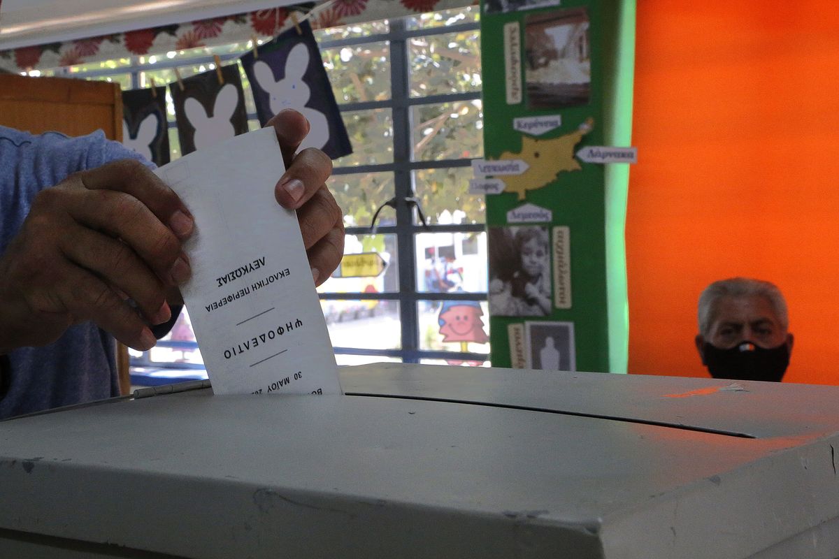 Electoral staff wearing face protective masks, observe as a voter casts his vote at a polling station during the parliamentary elections in Deftera, a suburb of capital Nicosia, Cyprus, Sunday, May 30, 2021. Cypriots are voting for a new parliament, with some 558,000 voters eligible to elect 56 lawmakers.  (Petros Karadjias)