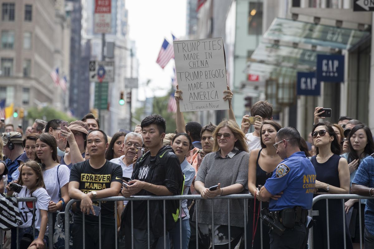 People including a protestor holding a sign line Fifth Avenue as they watch President Donald Trump’s motorcade leave Trump Tower, Wednesday, Aug. 16, 2017, in New York. (Mary Altaffer / Associated Press)