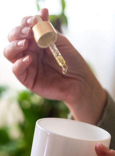 Woman carefully drops cbd oil into a tea cup.  (Shutterstock)