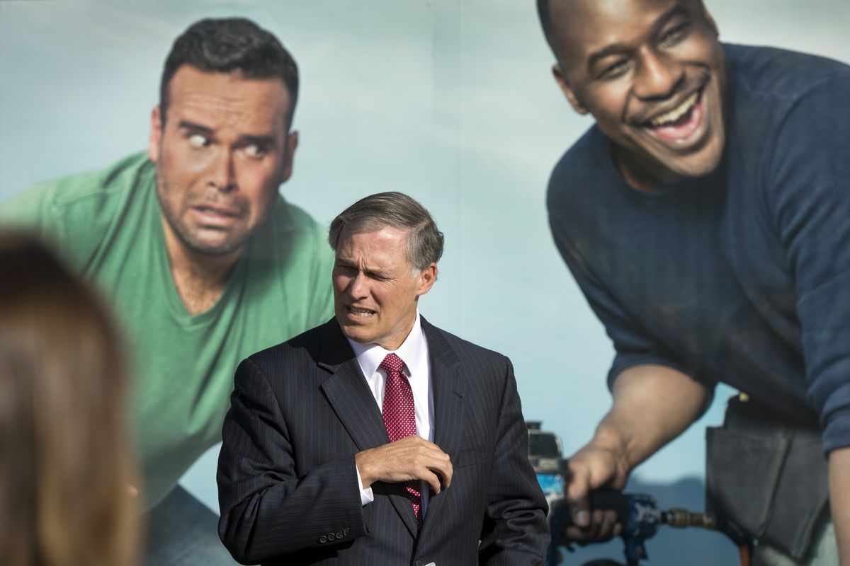 Washington Gov. Jay Inslee pauses in front of the Washington Health Plan Finder Mobile Enrollment Tour trailer before addressing the crowd at the Native Project Clinic on Wednesday in Spokane. The mural shows a man with a nail gun injuring the man on the left. The governor made stops throughout Spokane while the trailer made its first stop before heading out across the state. (Dan Pelle)