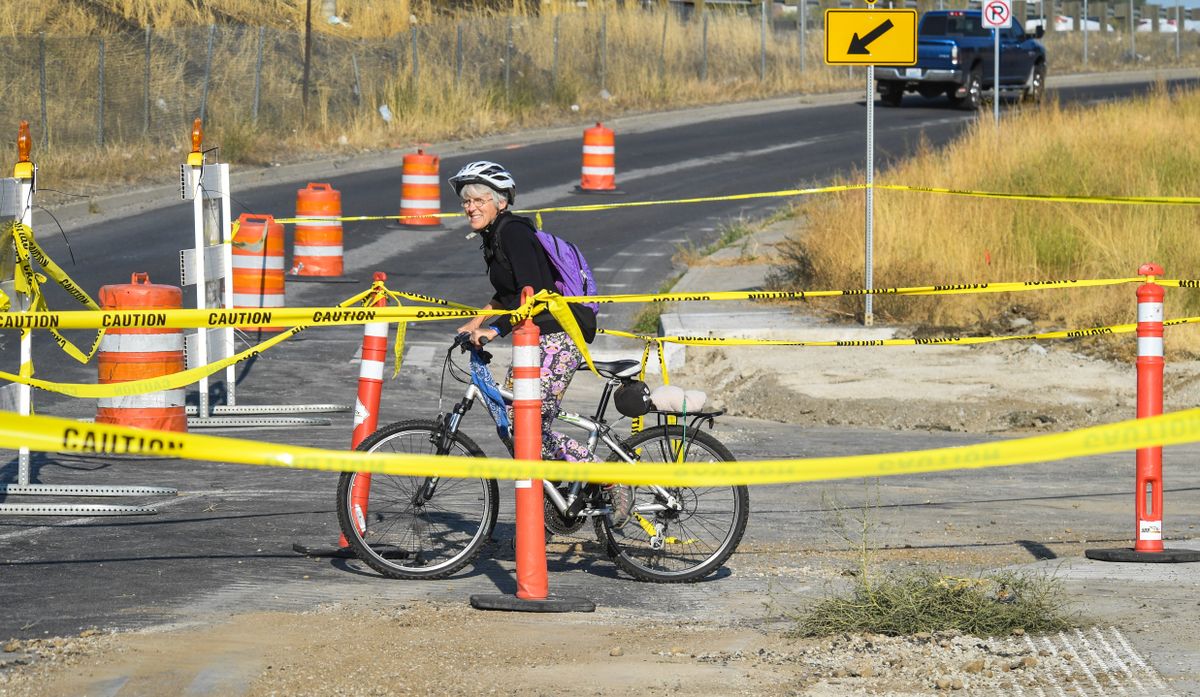 Cyclist Susan Hale waits for an opening in traffic to cross north on Perry Street at 3rd Avenue as work is underway for pedestrian safety construction of hybrid beacons along the Ben Burr Trail, Wednesday, Sept. 30, 2020 in Spokane. The project is budgeted for $363,000.  (DAN PELLE)