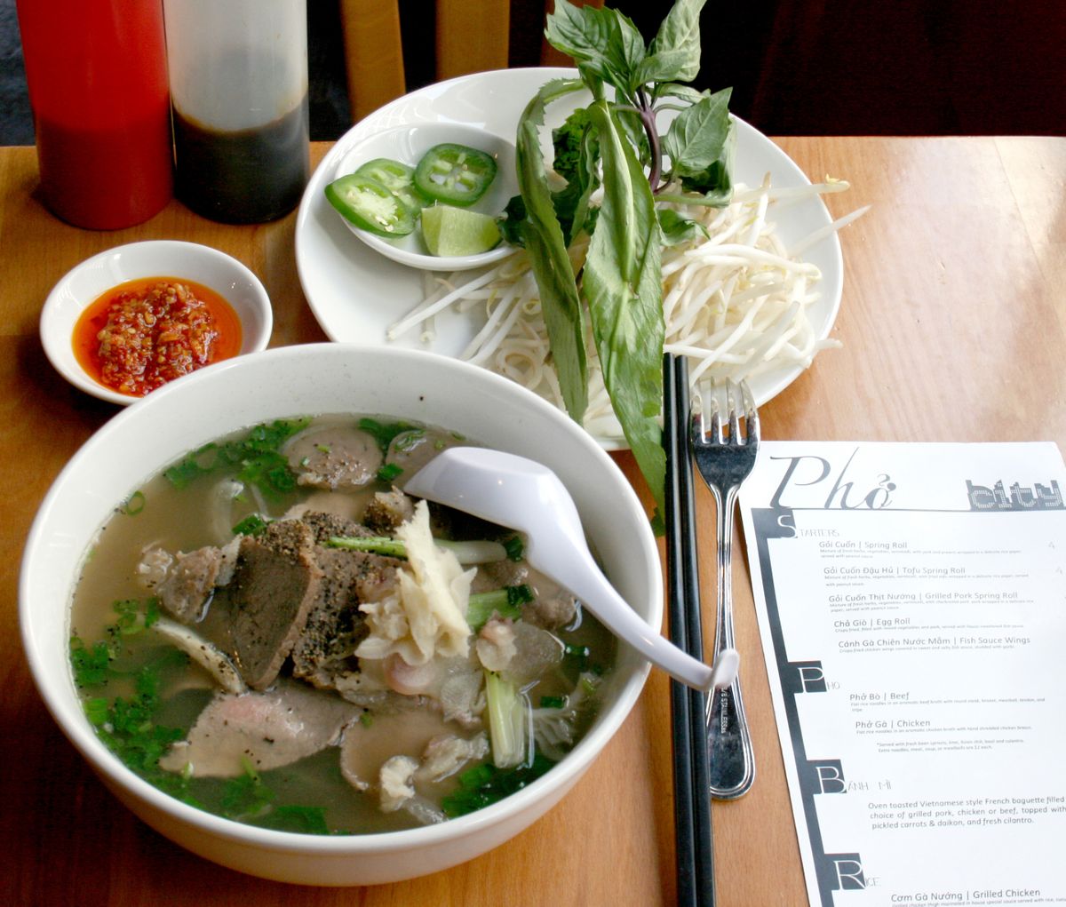 At Pho City, you’ll find a steaming bowl of noodles swimming in broth with a plate filled with bean sprouts, sprigs of culantro (a relative of cilantro) and Thai basil, a few slices of fresh jalapeno pepper and a wedge of lime, as well as a small dish of house-made red chili paste.
