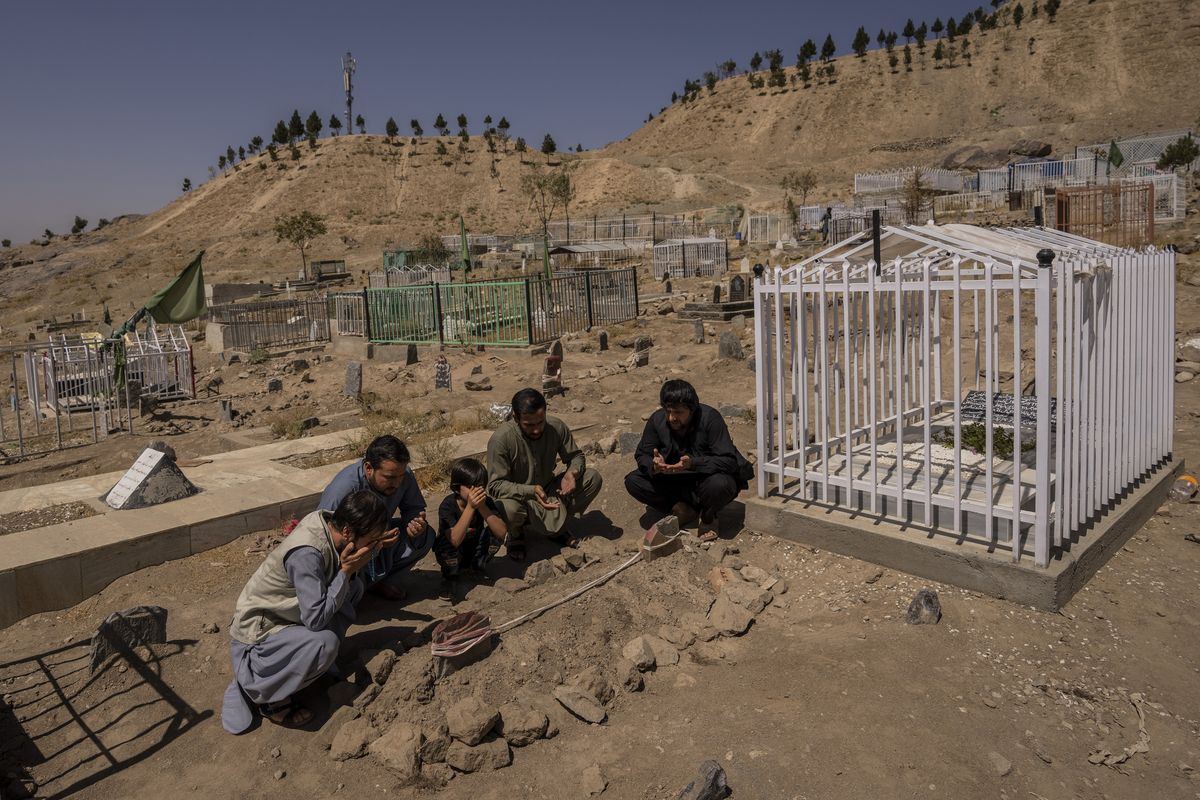 In this Monday, Sept. 13, 2021 photo, the Ahmadi family pray at the cemetery next to family graves of family members killed by a US drone strike, in Kabul, Afghanistan. Sorry is not enough for the Afghan survivors of an errant U.S. drone strike that killed 10 members of their family, including seven children. On Saturday, Sept. 18, they demanded Washington investigate who fired the drone and punish the military personnel responsible for the strike, said Emal Ahmadi, whose 3-year-old daughter Malika was killed on Aug. 29 when the U.S. hellfire missile struck his elder brother