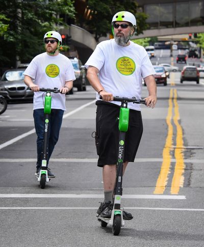 Lime employees Kelly Lotze and James Langford ride on Howard Street during the kickoff of the Lime Patrol in June 2019.  (DAN PELLE)