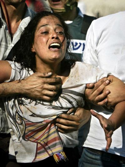 
An Israeli woman is helped at the scene of a rocket attack. 
 (Associated Press / The Spokesman-Review)
