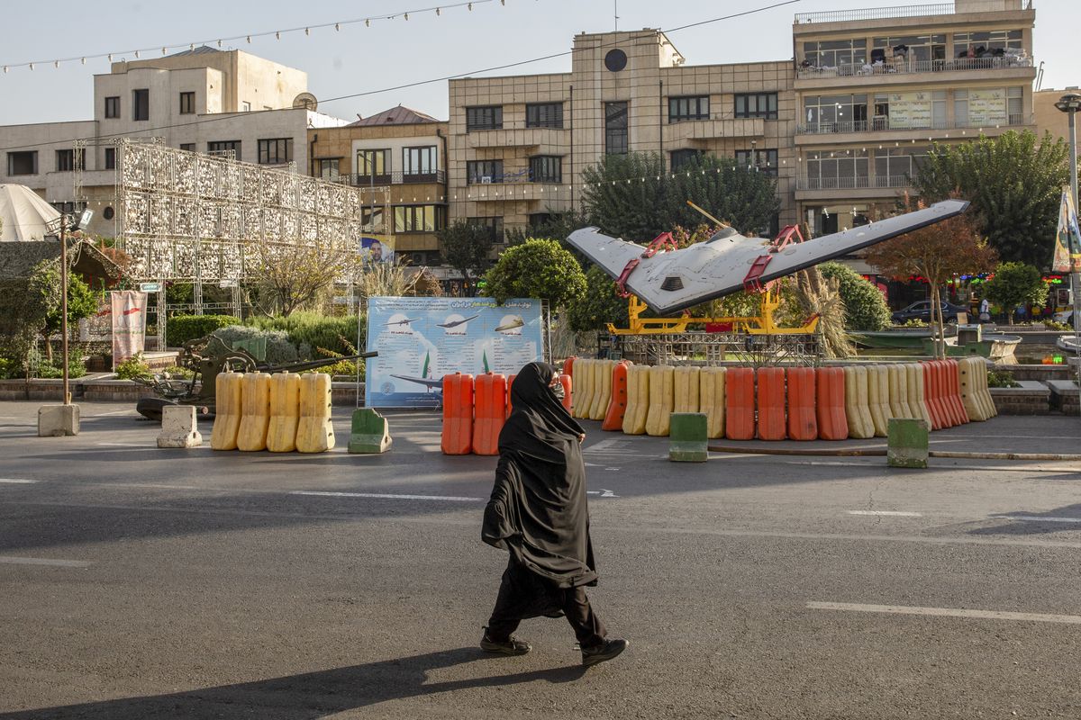 FILE -- A woman walks past an Iranian Shahed drone displayed at a military exhibit in Tehran, Iran, Oct. 1, 2026. Iran