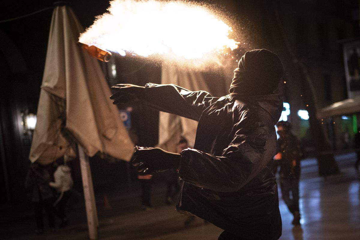 A protestor throws a molotov cocktail at police during clashes following a protest condemning the arrest of rap singer Pablo Hasél in Barcelona, Spain, Saturday, Feb. 27, 2021. After a few days of calm, protests have again turned violent in Barcelona as supporters for a jailed Spanish rapper went back to the streets.  (Emilio Morenatti)