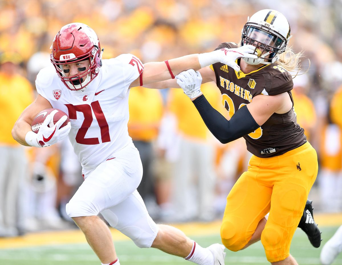 Washington State Cougars running back Max Borghi (21) facemarks Wyoming Cowboys safety Andrew Wingard (28) during the first half of a college football game on Saturday, September 1, 2018, at War Memorial Stadium in Laramie, Wyo. (Tyler Tjomsland / The Spokesman-Review)